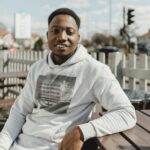 About Smiling adult man in a hoodie outdoors, enjoying a sunny day.